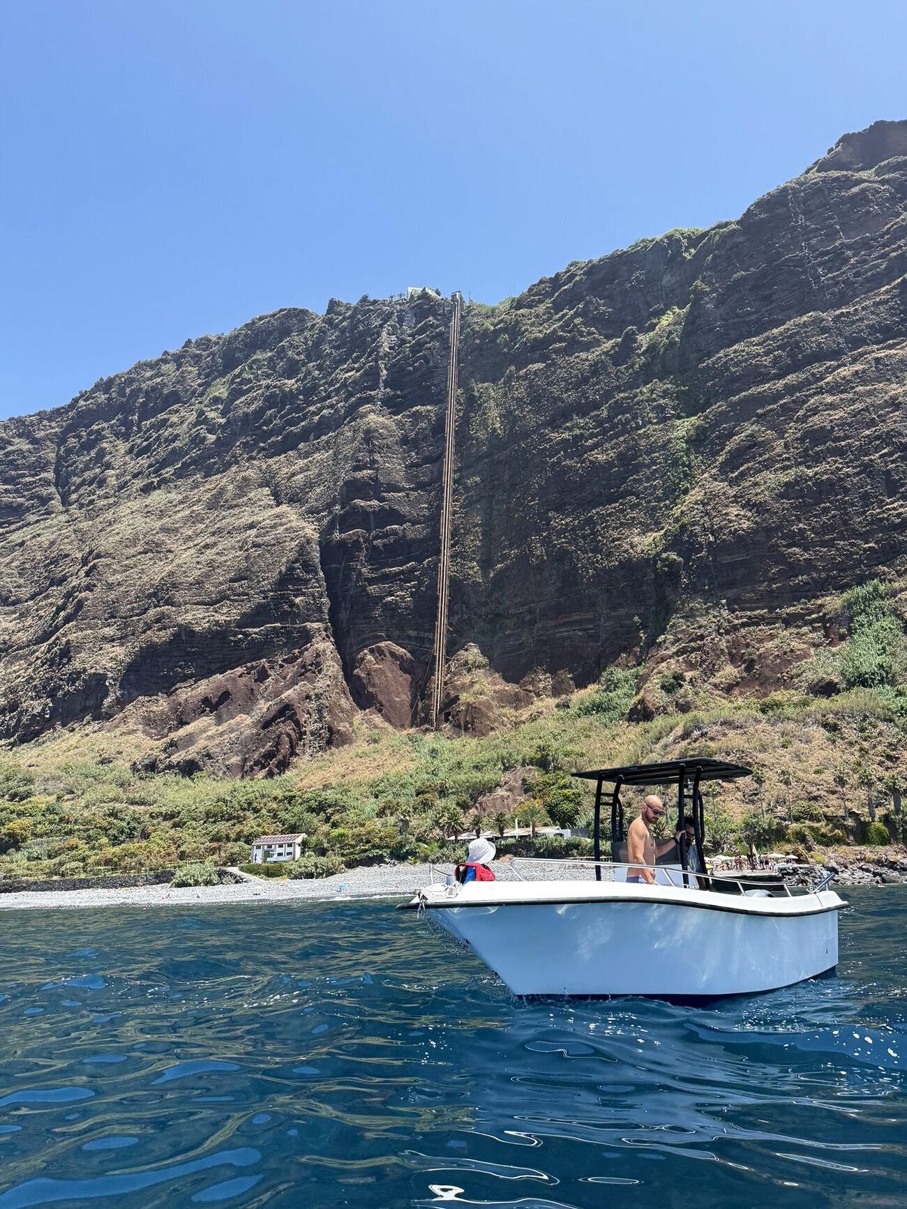 Boa Vida's boat anchored by the cliffs while guests swim and snorkel